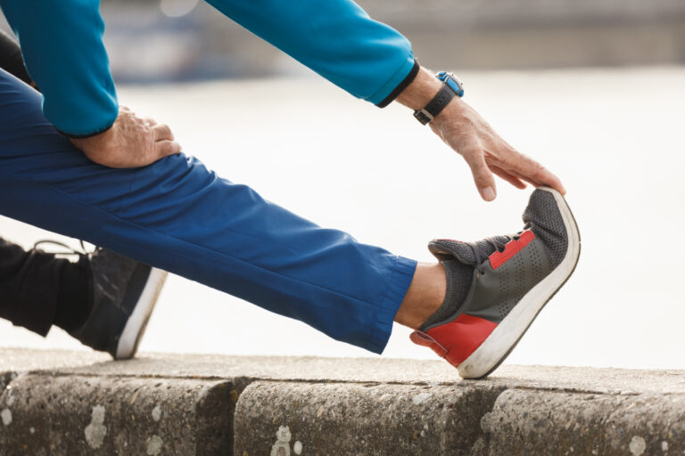 Person stretching a hamstring with one foot resting on a low wall