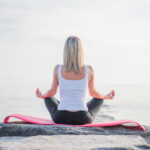 Woman meditating cross-legged on a rock by the sea
