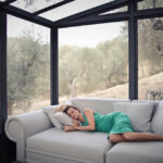 Woman napping peacefully on a sofa in a bright sunroom