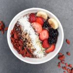 Smoothie bowl topped with strawberries, banana, coconut and goji berries