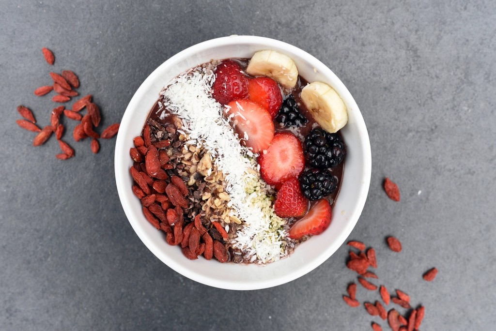 Smoothie bowl topped with strawberries, banana, coconut and goji berries